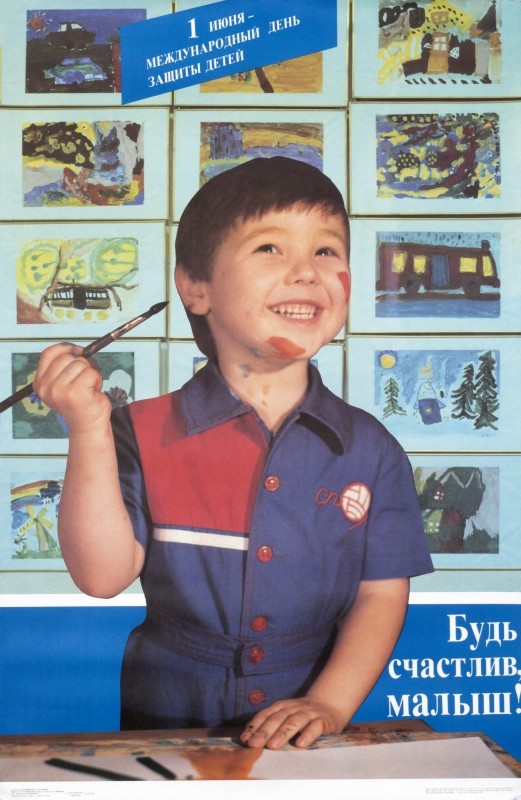 Little boy covered in paint draws w/brush; blue, red, green Yellow