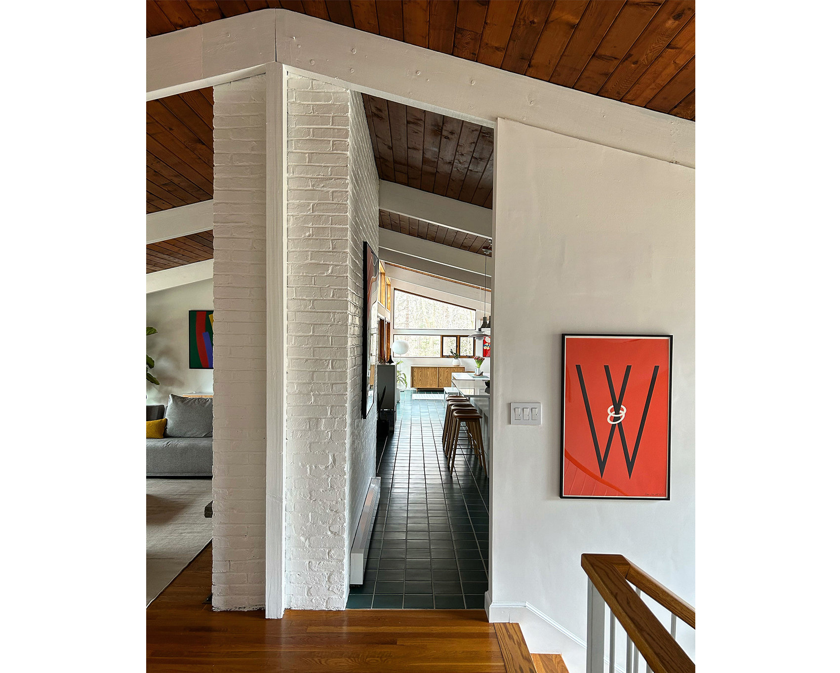 photo of framed alphabet poster w near top of stairs with long view of kitchen through doorway