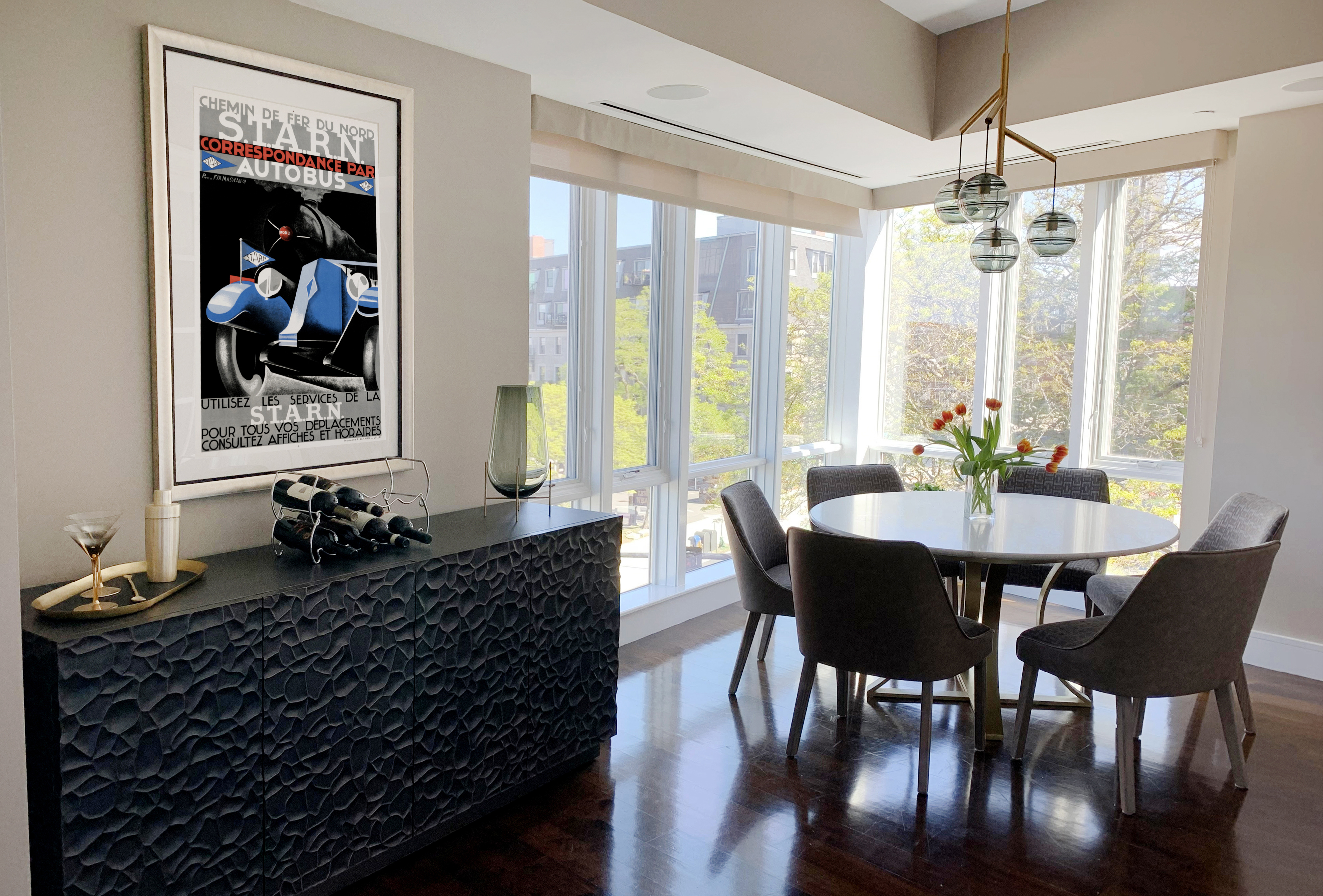 well-lit room with round table and chairs and poster on wall